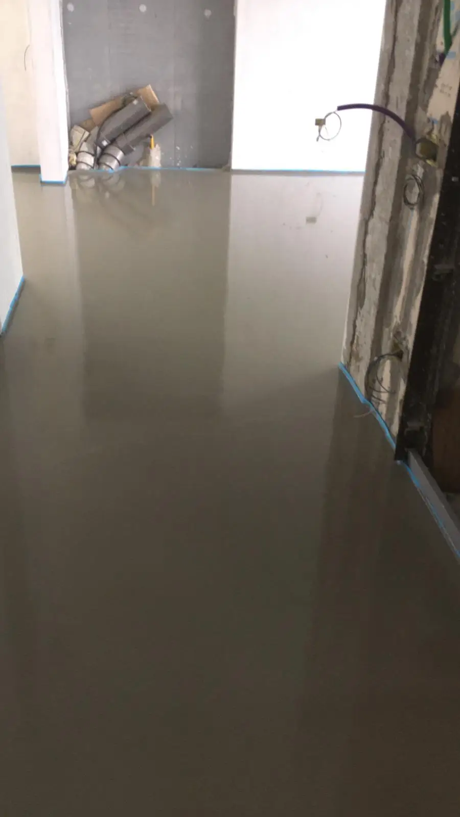 Superficie riflettente del massetto in un passaggio tra locali in ristrutturazione.