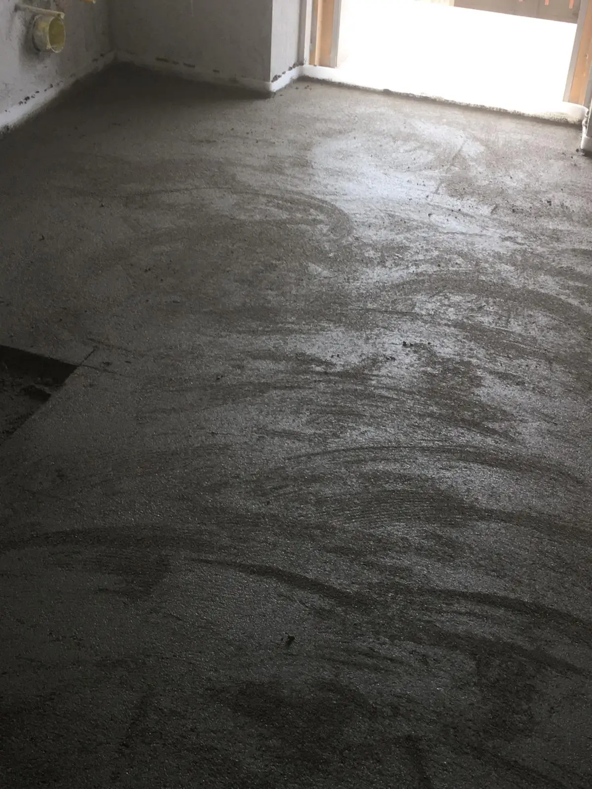 Tracce circolari di lavorazione sulla superficie del massetto vicino alla portafinestra.