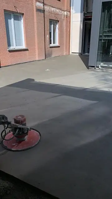 Frattazzatrice sul massetto esterno, accanto alla facciata in mattoni dell'edificio.