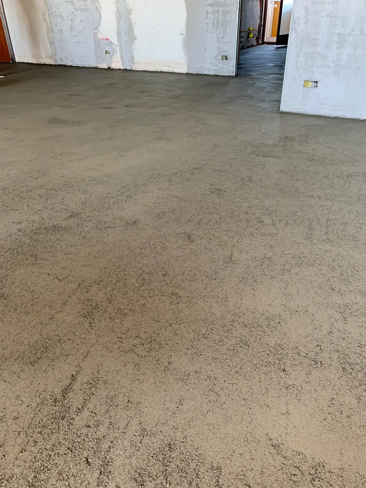 Dettaglio della superficie del massetto davanti alle porte interne di un'abitazione in ristrutturazione.