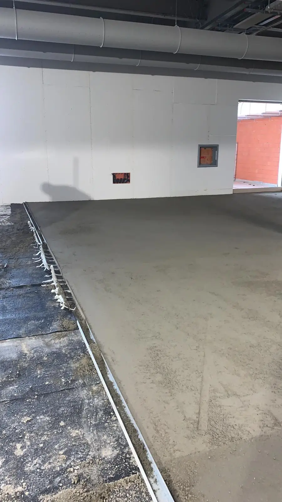 Bordo della superficie appena stesa, con staggia e telo di separazione nel locale di cantiere.